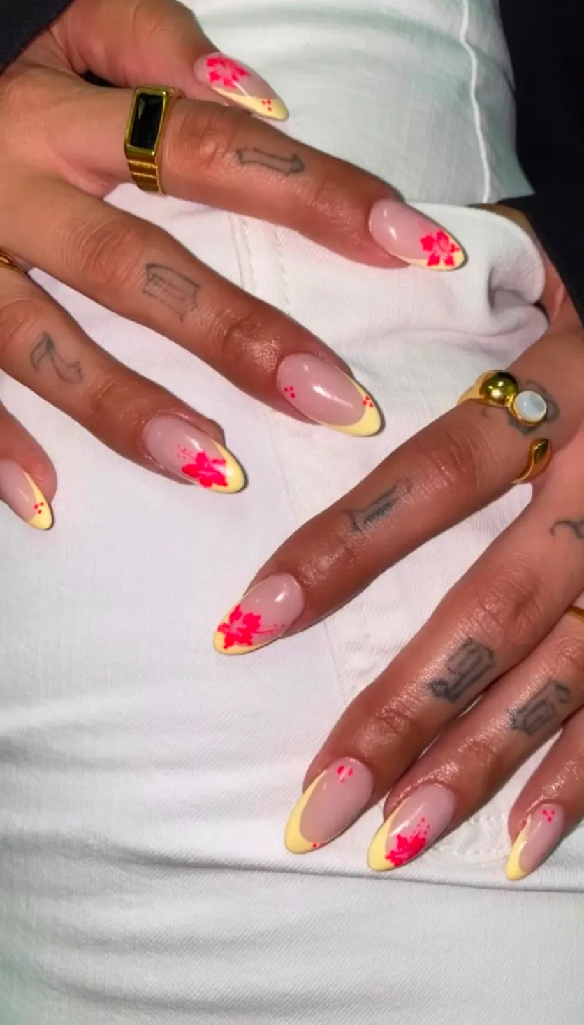 Unhas amendoadas nude com pontas amarelas e flores vermelhas pintadas à mão