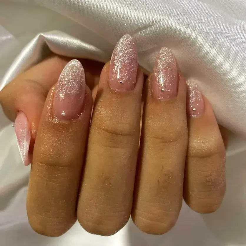 Unhas amendoadas rosa perolado com brilho e pequenos cristais